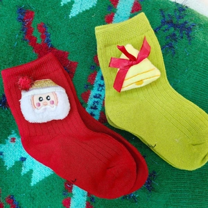 Festive Christmas baby socks with 3D Santa and bell dolls on green knit background