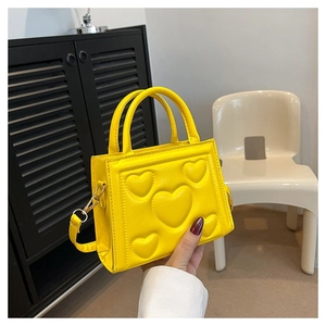 Détail du petit sac jaune avec motif de cœurs gaufrés et bandoulière réglable
