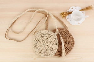 Detail of round paper rope woven bags with tassels in beige and light coffee shades