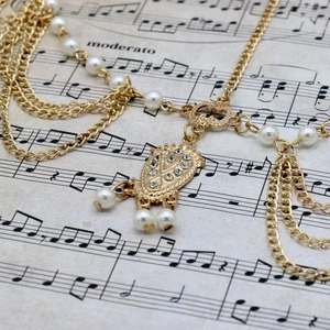 Detail of gold pearl chain headband with rhinestone pendant on vintage sheet music
