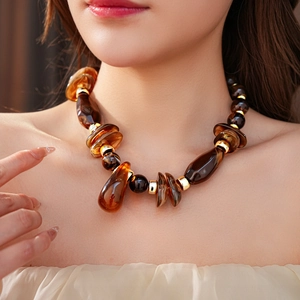 Dettaglio delle perle d'ambra e accenti dorati su una collana elegante indossata da una modella