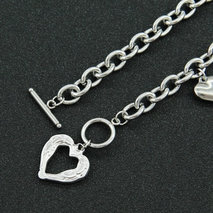 Silver OT clasp chain necklace with hollow and solid heart pendants on black background