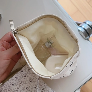 Close-up of small floral cotton makeup bag interior with perfume and powder