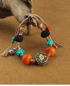 Close-up of Tibetan woven bracelet with cloud pattern beads and carved gourd pendant