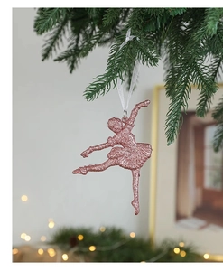 Close-up of rose gold glitter ballerina ornament hanging on a green Christmas tree branch