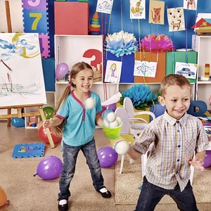 Children playing with white wool felt snowballs and green bucket in a festive room