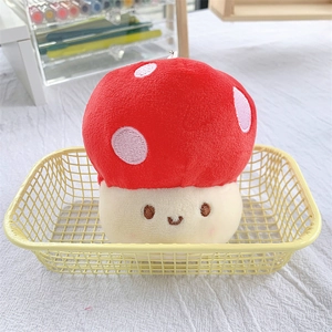 Close-up of a red plush mushroom keychain with a smiling face in a yellow basket