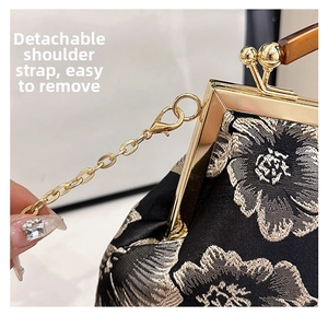 Close-up of golden vintage clasp and detachable metal chain on embroidered black bag