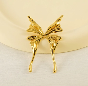 Macro view of minimalist butterfly wing earrings in a polished gold finish on stand