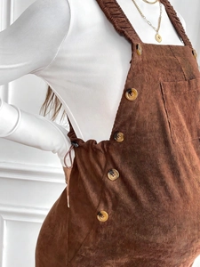 Detail of brown corduroy maternity overalls with side amber buttons and pocket