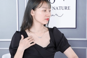 Detail of silver Libra constellation necklace in gothic font on a model neck