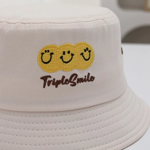 Kids cream cotton bucket hat featuring three yellow smiles and TripleSmile embroidery