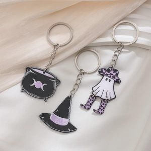 Detail shot of three Halloween enamel keychains with witch hat, ghost and cauldron elements