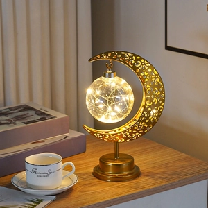 Lampe de table lune dorée avec guirlande lumineuse chaleureuse dans une chambre douillette