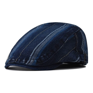 Close-up of blue patchwork denim flat cap with striped texture and side adjustable buckle
