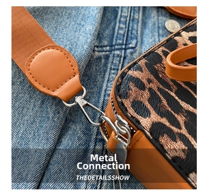 Macro detail of silver metal hook connecting orange shoulder strap to leopard print bag