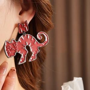 Close-up of red enamel cat earrings worn by a model showcasing detailed minimalist design