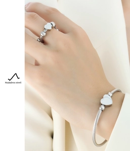 Detailed view of silver stainless steel heart ring and twisted cable wire bracelet set