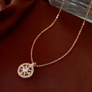 Gold plated compass necklace with white zircon pendant on dark silk fabric