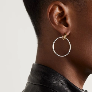 Close-up of two-tone gold and silver interlocking hoop earrings on a model's ear