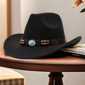 Dettaglio del cappello in feltro nero con perle turchesi su un tavolo di legno rustico