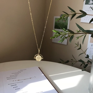 Macro detail of gold hexagon rotating pendant with star engraving on fine chain necklace