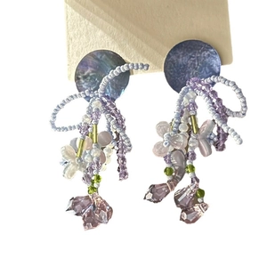 Floral beaded drop earrings with purple crystals and shell accents on a white background