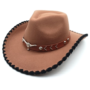 Detail of brown cowboy hat featuring metal bull head buckle and black woven edge