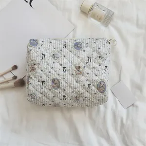 Détail d'une trousse à maquillage matelassée à motifs d'ours sur tissu rayé