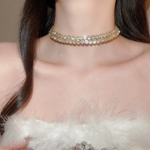 Close-up of a wide gold-tone choker necklace with wavy rows of sparkling rhinestones
