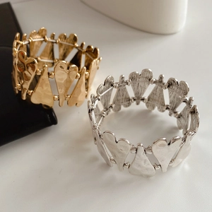 Gros plan de bracelets élastiques en forme de cœur dorés et argentés à texture martelée