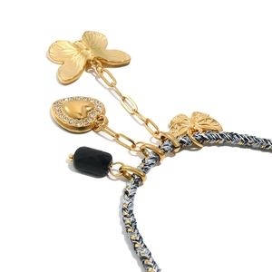 Dettaglio del bracciale in corda intrecciata con ciondoli a farfalla dorata e cuore