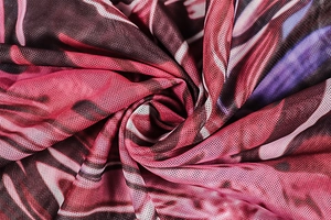 Detailed close-up of semi-sheer mesh fabric with red and purple abstract print patterns
