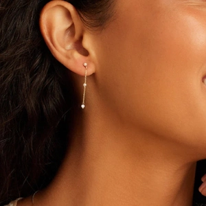 Close-up of elegant long tassel gold chain earrings with pearls worn by a model
