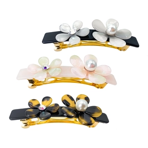 Close-up of three floral hair clips with acetate petals, rhinestones, and pearls details