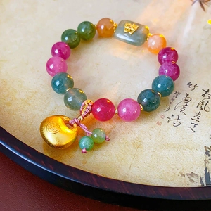 Detail of colorful beaded bracelet with gold butterfly and lucky lock charm