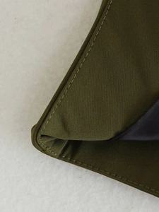 Macro view of olive green fabric texture and double needle stitching detail on the vest