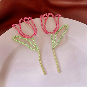 Detail of tulip earrings with pink crystals and green leaves on a gold base