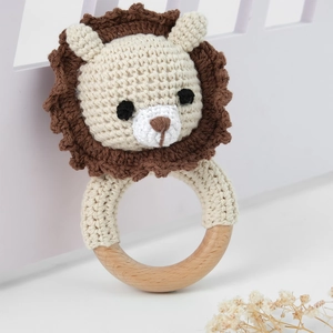 Detail of handmade crochet lion rattle with natural wooden ring for baby teething