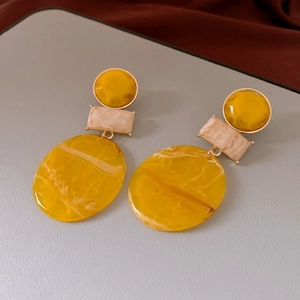 Detail of yellow and beige marble resin geometric earrings with gold-toned metal trim