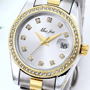 Close-up of a silver and gold stainless steel watch face with crystal bezel and date window