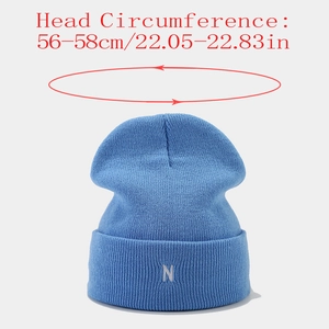 Vue détaillée de la broderie blanche de la lettre N sur ce bonnet bleu en tricot