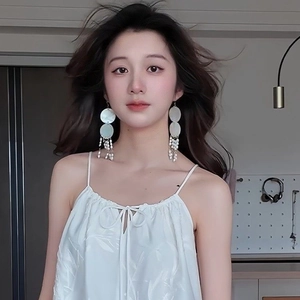 Elegant long fringe pearl earrings with natural mother of pearl discs on a female model