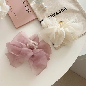 Close-up of pink and white organza bow hair claws with transparent acrylic clips