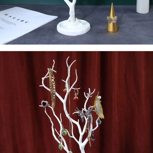 White tree-shaped jewelry organizer stand holding various necklaces and earrings