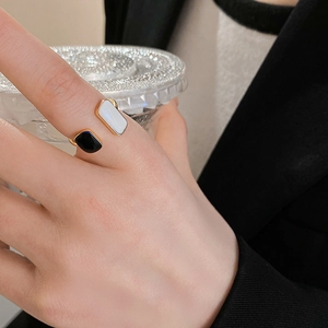 Close-up of adjustable gold ring with black and white geometric enamel rectangular charms
