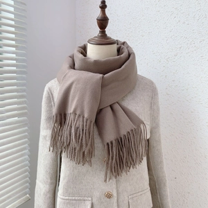 Detail of khaki faux cashmere scarf with tassels styled on a beige mannequin