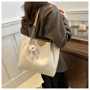 Dettaglio della borsa tote crema con finiture in pelle marrone e charm in peluche rosa