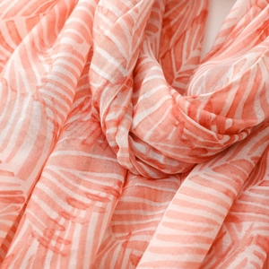 Close-up of coral pink leaf pattern on breathable bali yarn fabric with soft drape