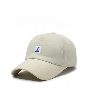 Detail of beige quilted baseball cap featuring a unique blue bird logo and square patch